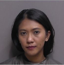 A woman with straight, shoulder length black hair and wearing a gray top is facing the camera against a plain background She has a neutral expression