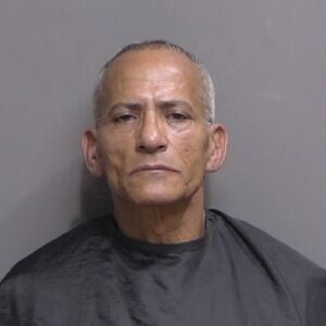 A middle aged man with short gray hair wearing a dark drape poses for a mugshot against a plain gray background A middle aged man with short gray hair wearing a dark drape poses for a mugshot against a plain gray background