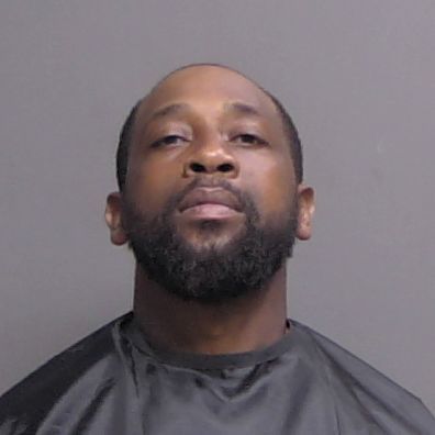 Mugshot of a man with a short beard against a gray background